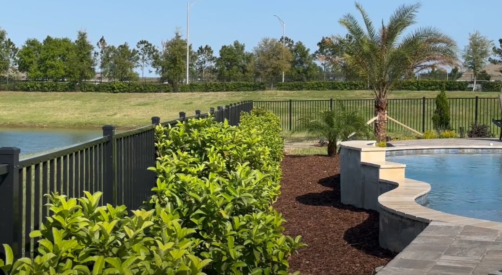 Waterfront landscape design featuring pool deck landscaping and tropical plant maintenance Waterfront property landscaping with pool area, palm trees, and professional plant care